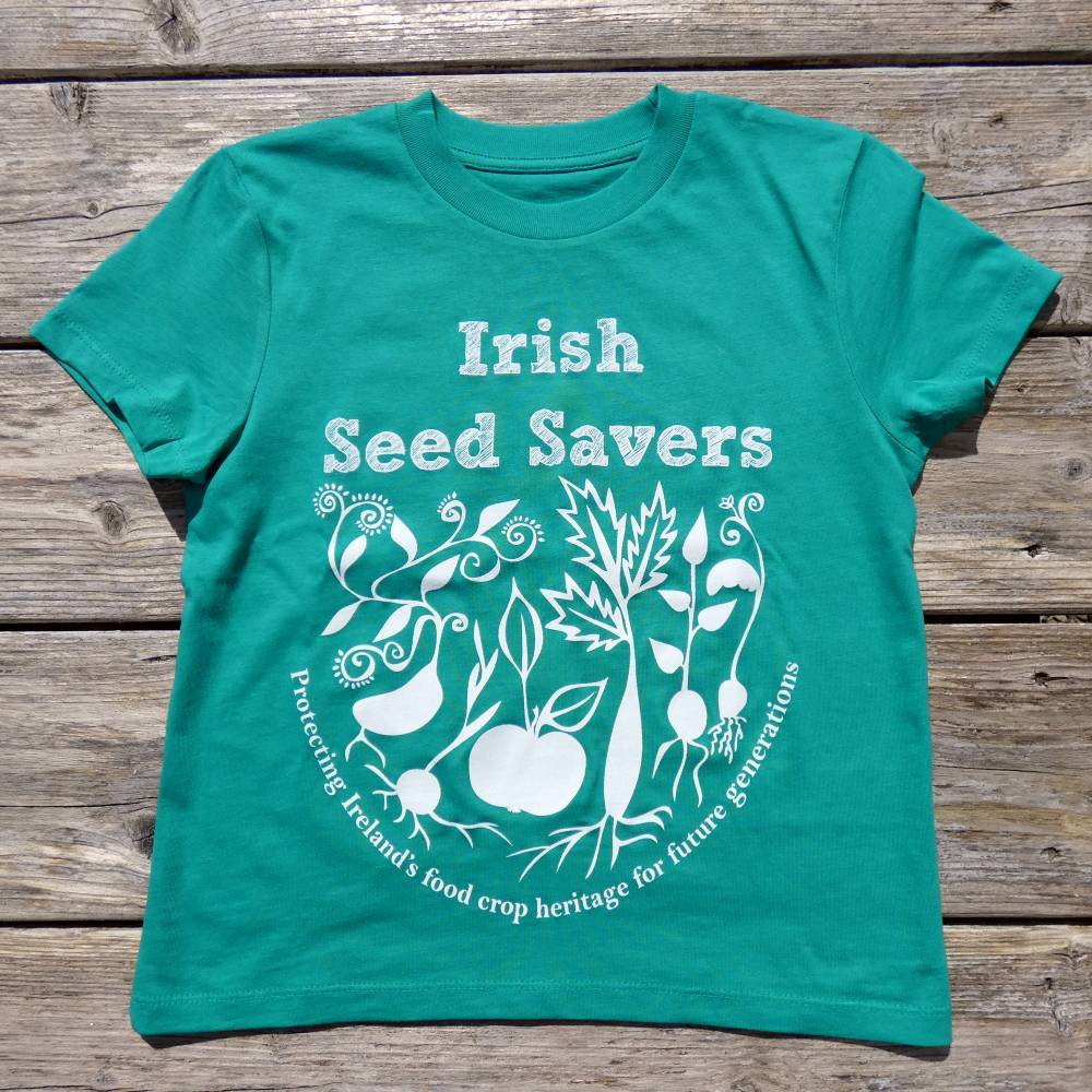 Green kids Tshirt with Irish Seed Savers logo lying flat on a wooden table.